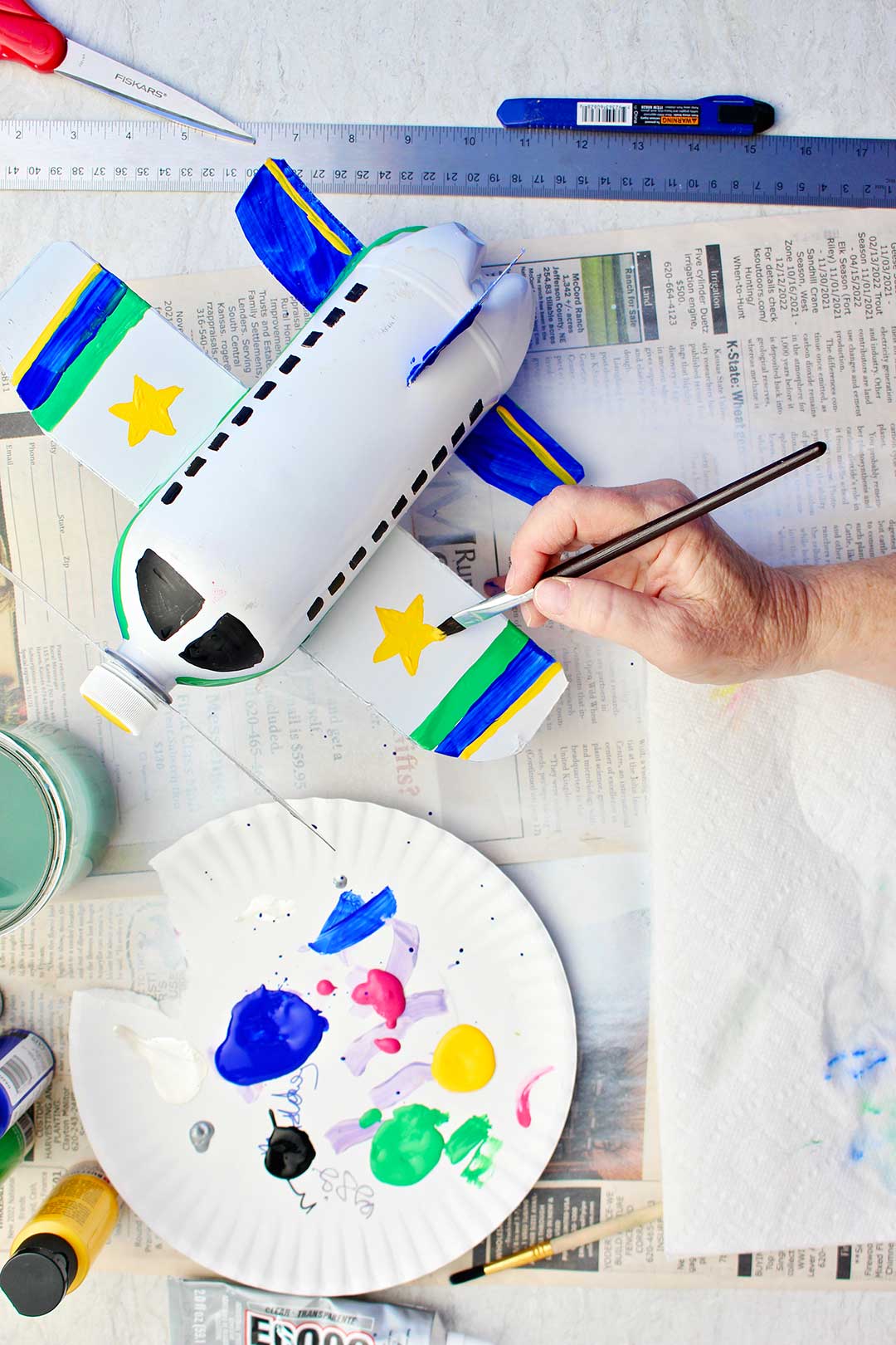 Pintando detalhes nas asas como listras e estrelas no avião de garrafa branco.
