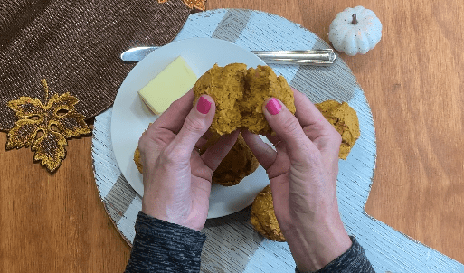 muffin de abóbora partido ao meio nas mãos de uma mulher