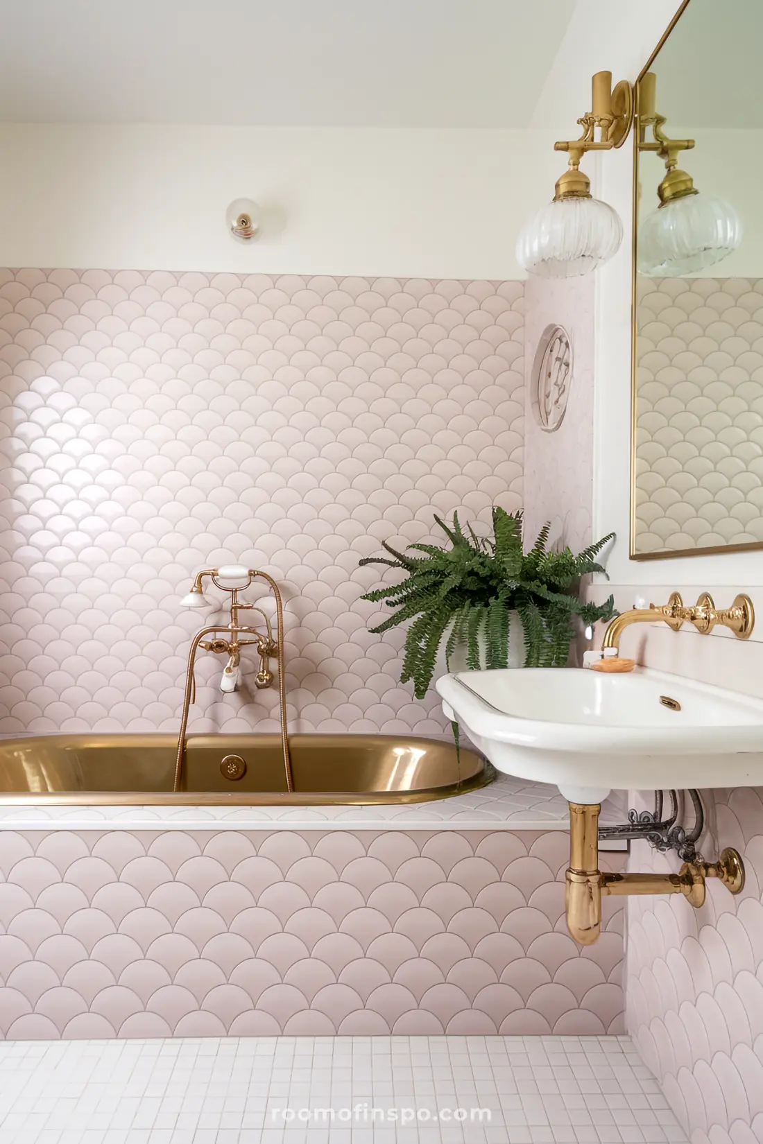 Banheiro com azulejos de sereia rosa, acabamentos dourados e decoração aconchegante.