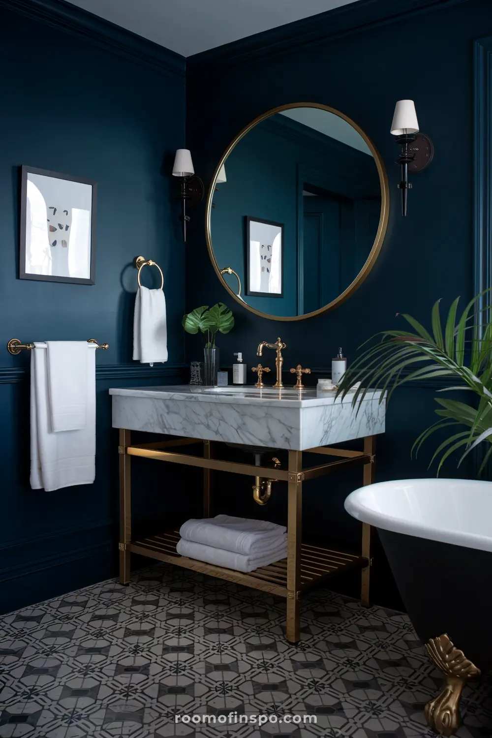 Um banheiro estiloso com paredes azul-escuras, um grande espelho redondo com moldura dourada, uma pia de mármore com torneiras douradas, toalhas brancas e elementos decorativos incluindo arte emoldurada e plantas.