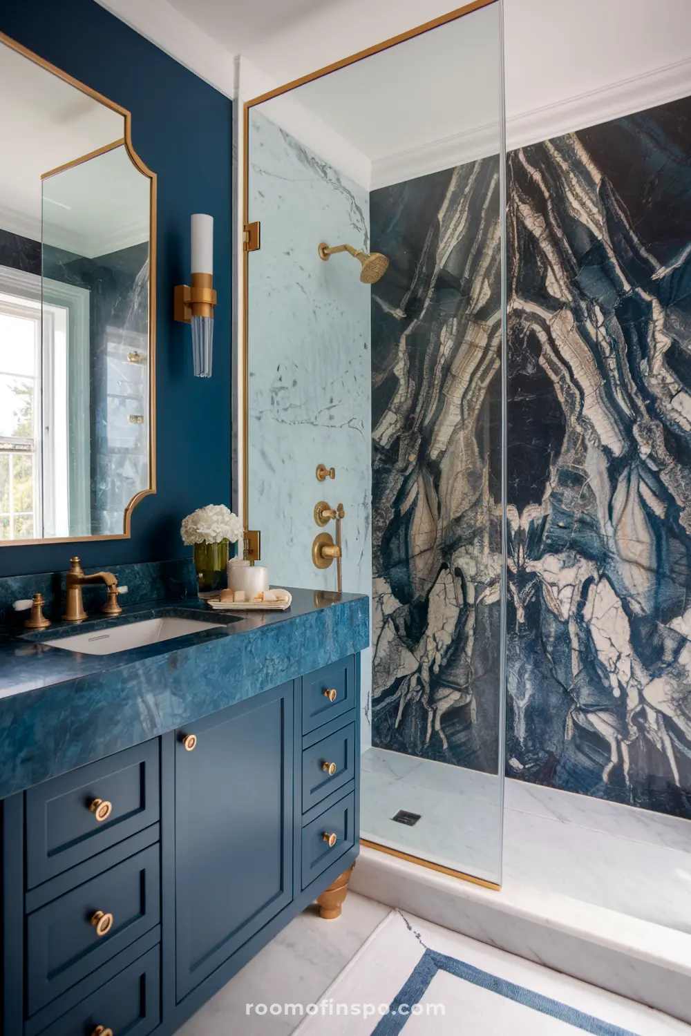 Um banheiro azul sombrio com uma vaidade de mármore azul, acessórios dourados e uma parede de chuveiro de mármore.