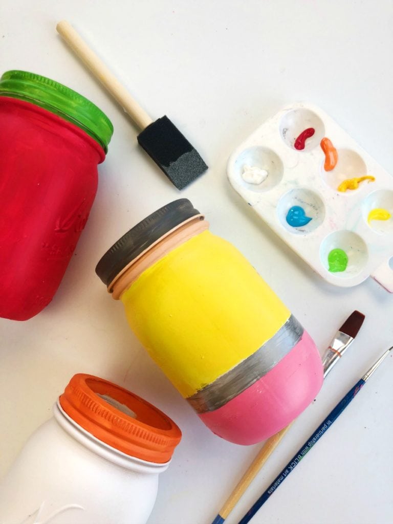 Jarras de conservas pintadas para parecerem materiais escolares - pincéis de diferentes tamanhos são mostrados