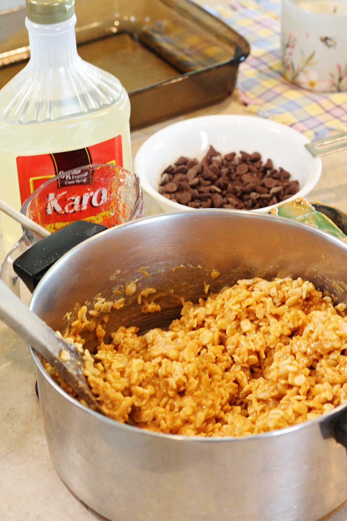 Mistura de arroz crocante em uma panela com gotas de chocolate e xarope Karo ao lado.