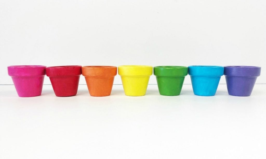 Uma paleta em arco-íris de vasos de flores pintados