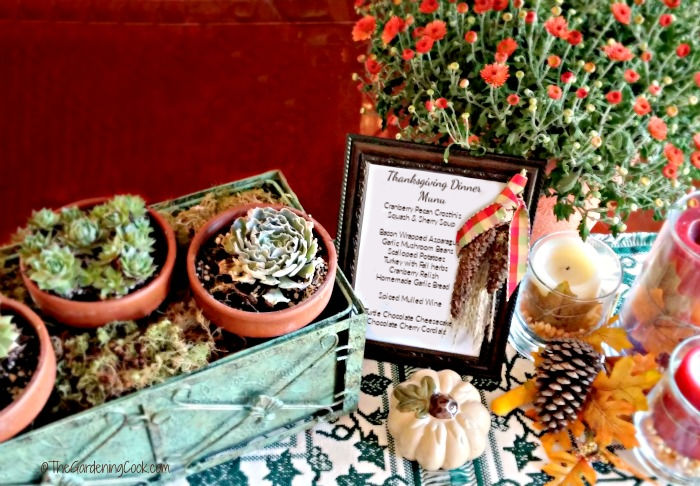Nosso cardápio de jantar de Ação de Graças. Plantas suculentas em um vaso verde com flores de outono, pequenas abóboras e um cardápio de Ação de Graças emoldurado.