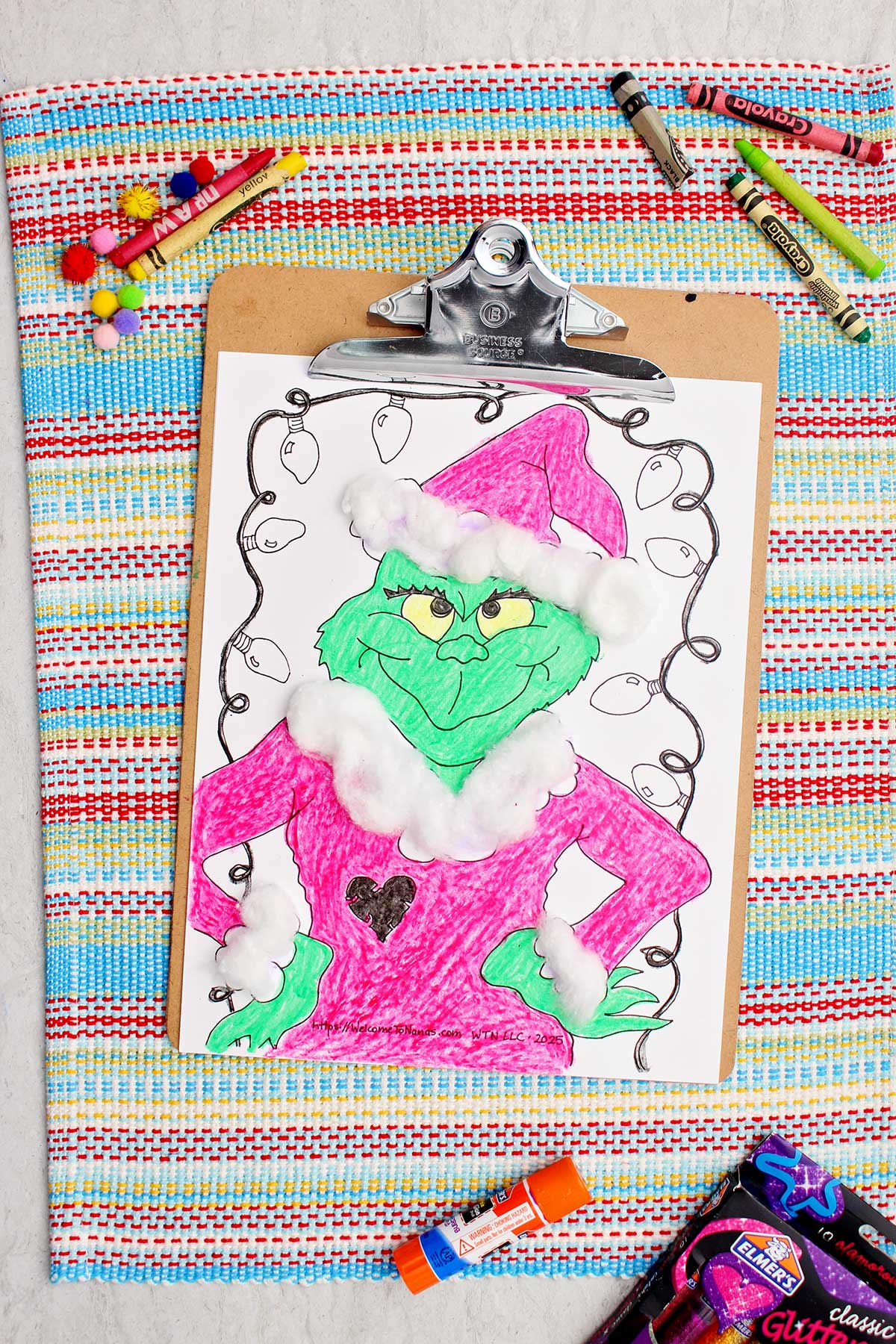 Grinch colorido impresso completo com acentos de bolinha de algodão presos em um prancheta.
