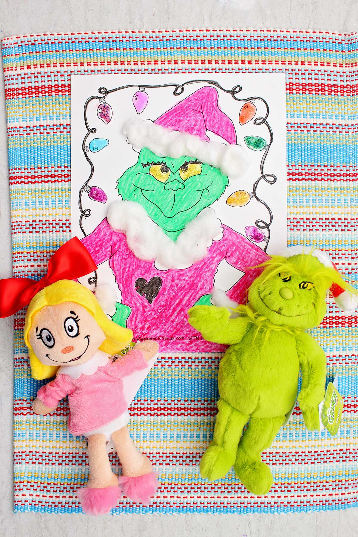 Página de colorir do Grinch completada com dois bichos de pelúcia do Grinch por perto.