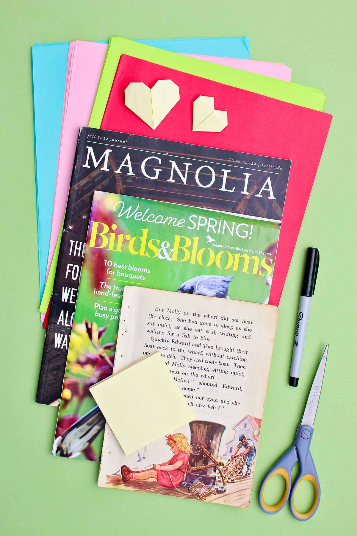Páginas de revistas e papéis coloridos, tesouras, marcador e notas adesivas.