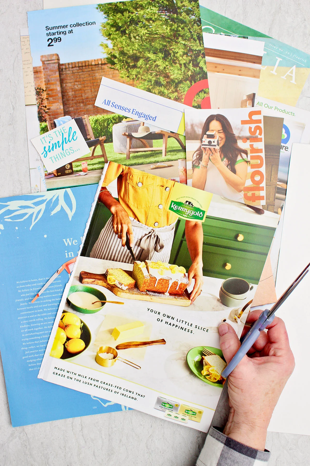 Uma pessoa segurando uma tesoura e alguns recortes de revistas coloridos para um quadro de visualização.