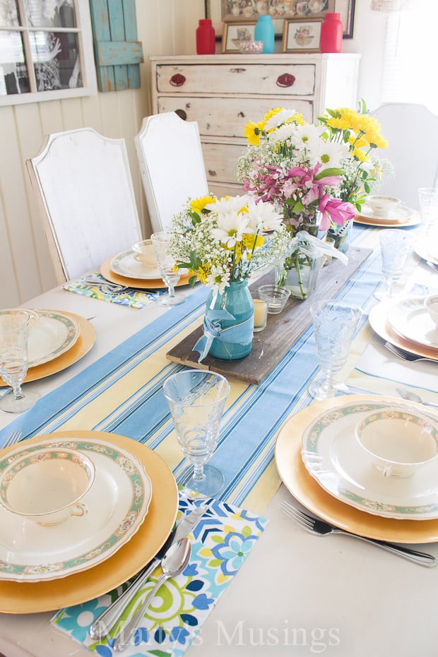 Um prato com um vaso de flores sobre uma mesa, com azul e amarelo