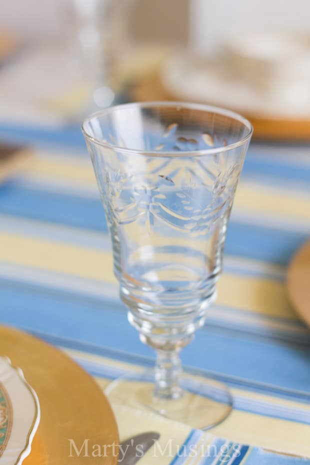 Uma xícara de vidro sobre uma mesa, com azul e flores