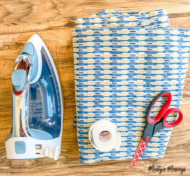 materiais para caminho de mesa sem costura com uma toalha antiga, fita para bainha e ferro de passar