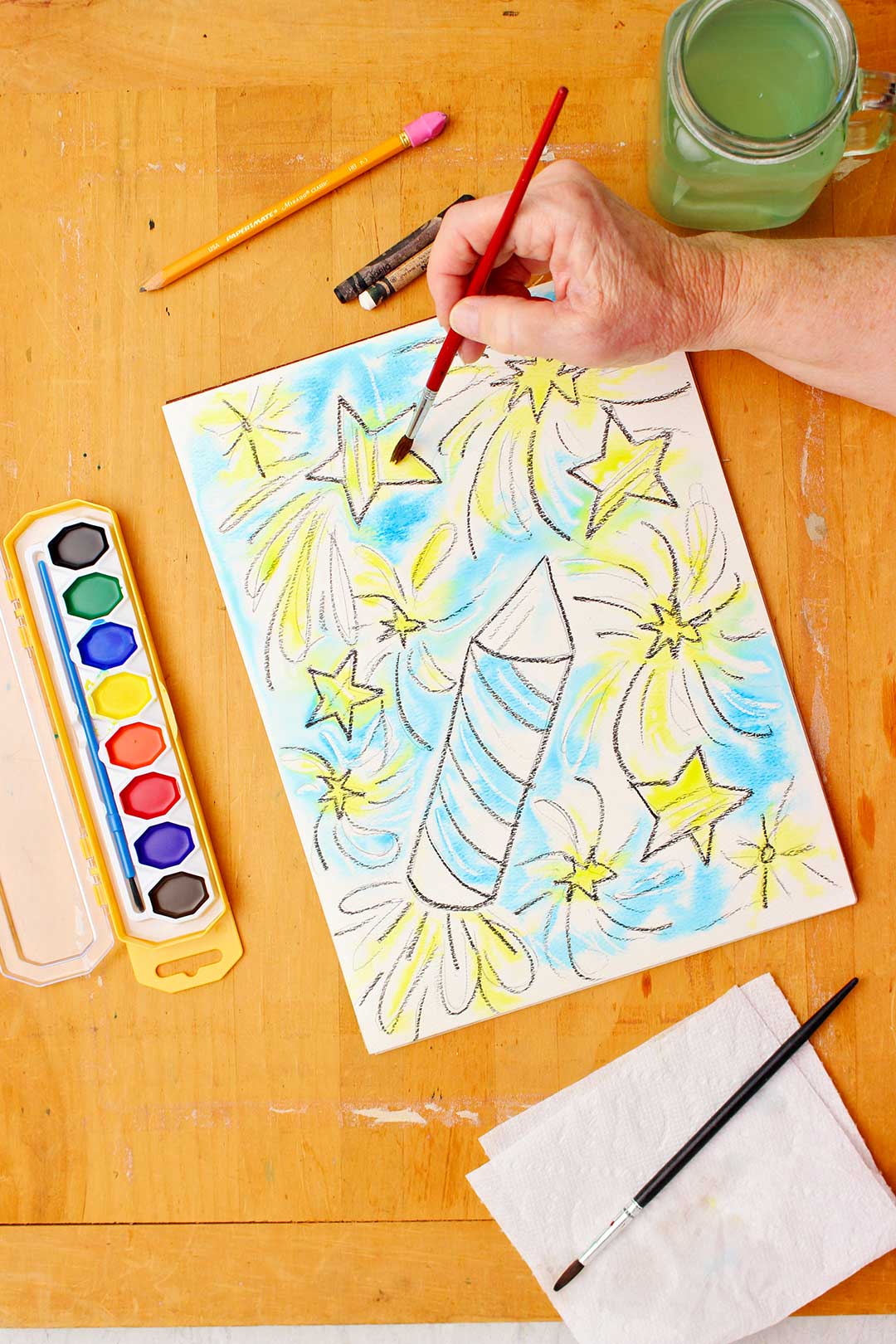 Mão pintando estrelas amarelas na resistência em aquarela.
