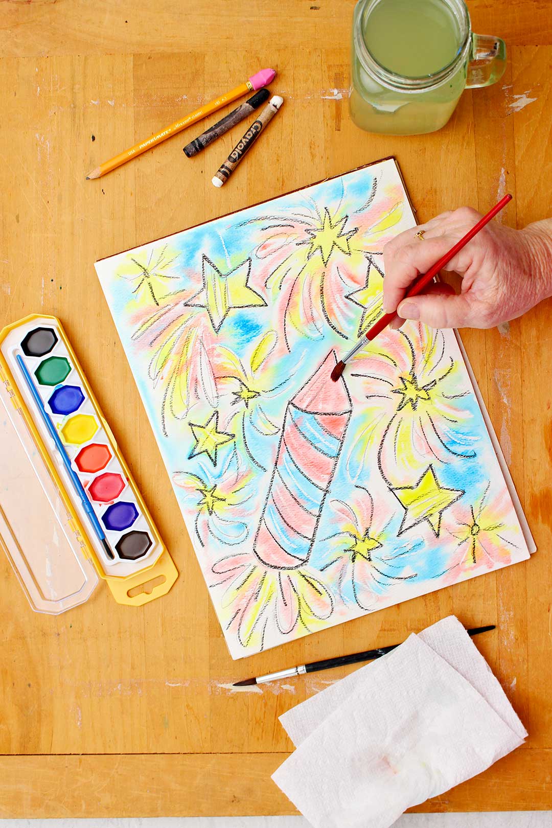 Mão pintando a ponta do foguete na resistência com aquarela.