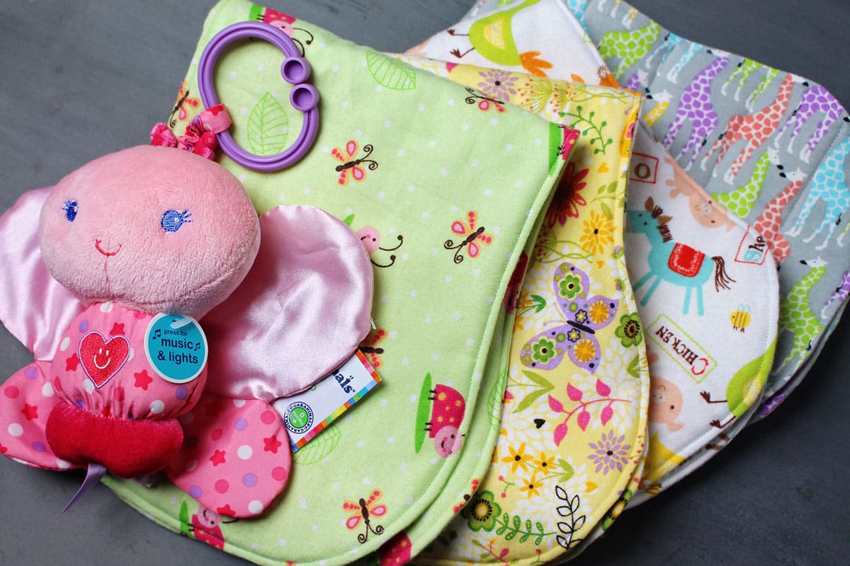 Uma pilha de toalhas de boca para bebês feitas de estampas de tecido de feltro colorido.