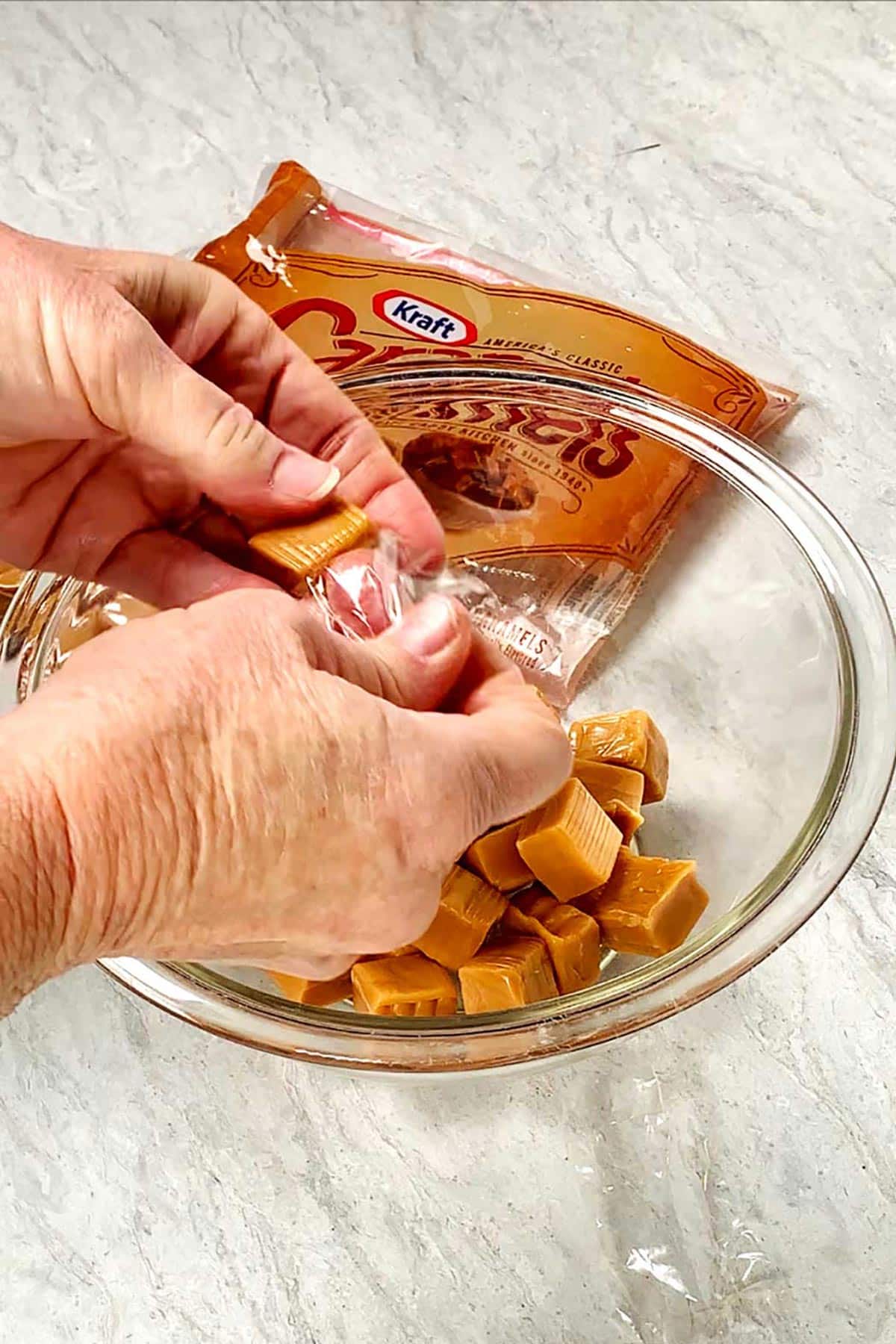 Pessoa desembrulhando Caramelos Kraft em uma tigela de vidro.