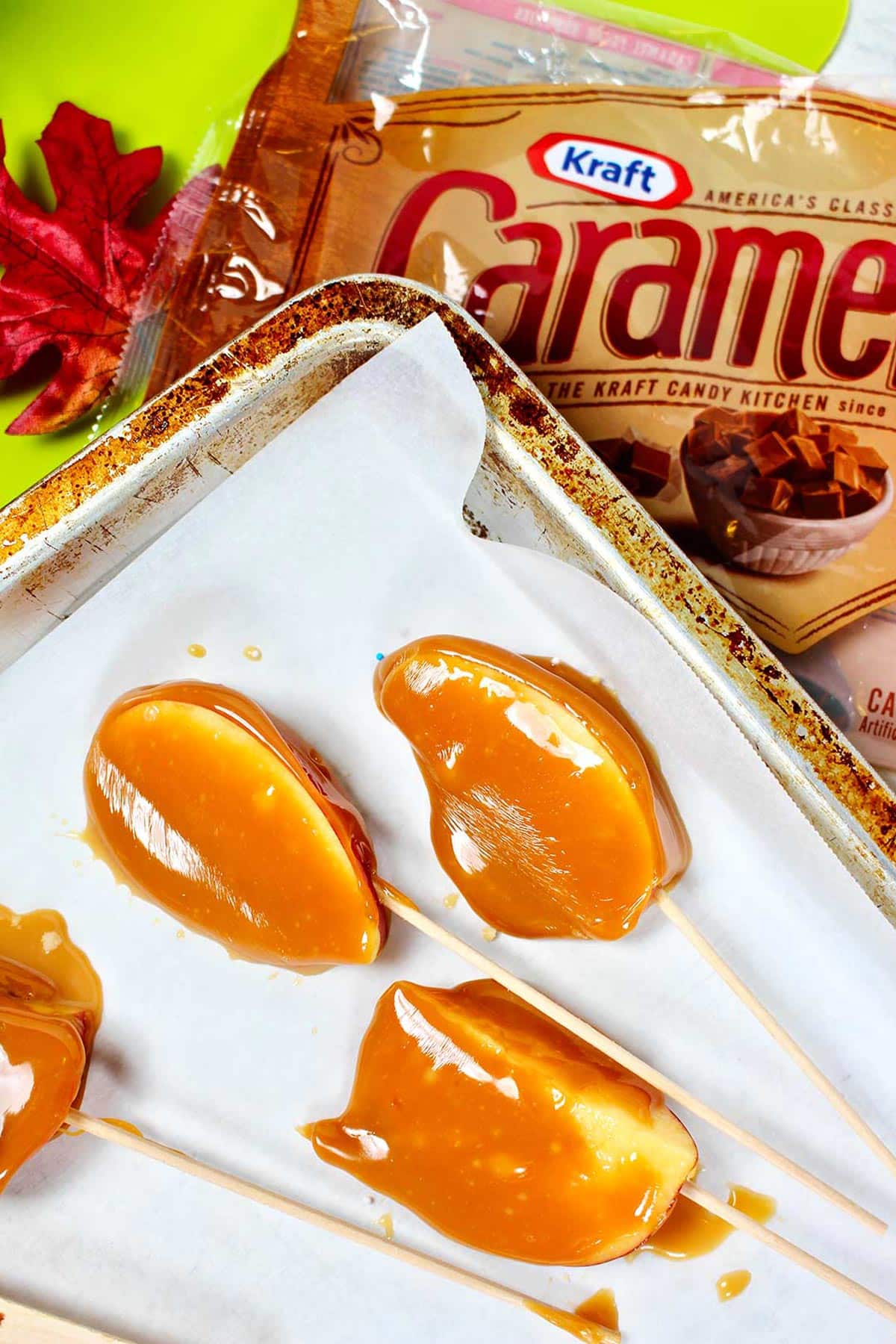 Fatias de maçã caramelizada sobre papel manteiga em cima de uma embalagem vazia de Kraft Caramel Bites.