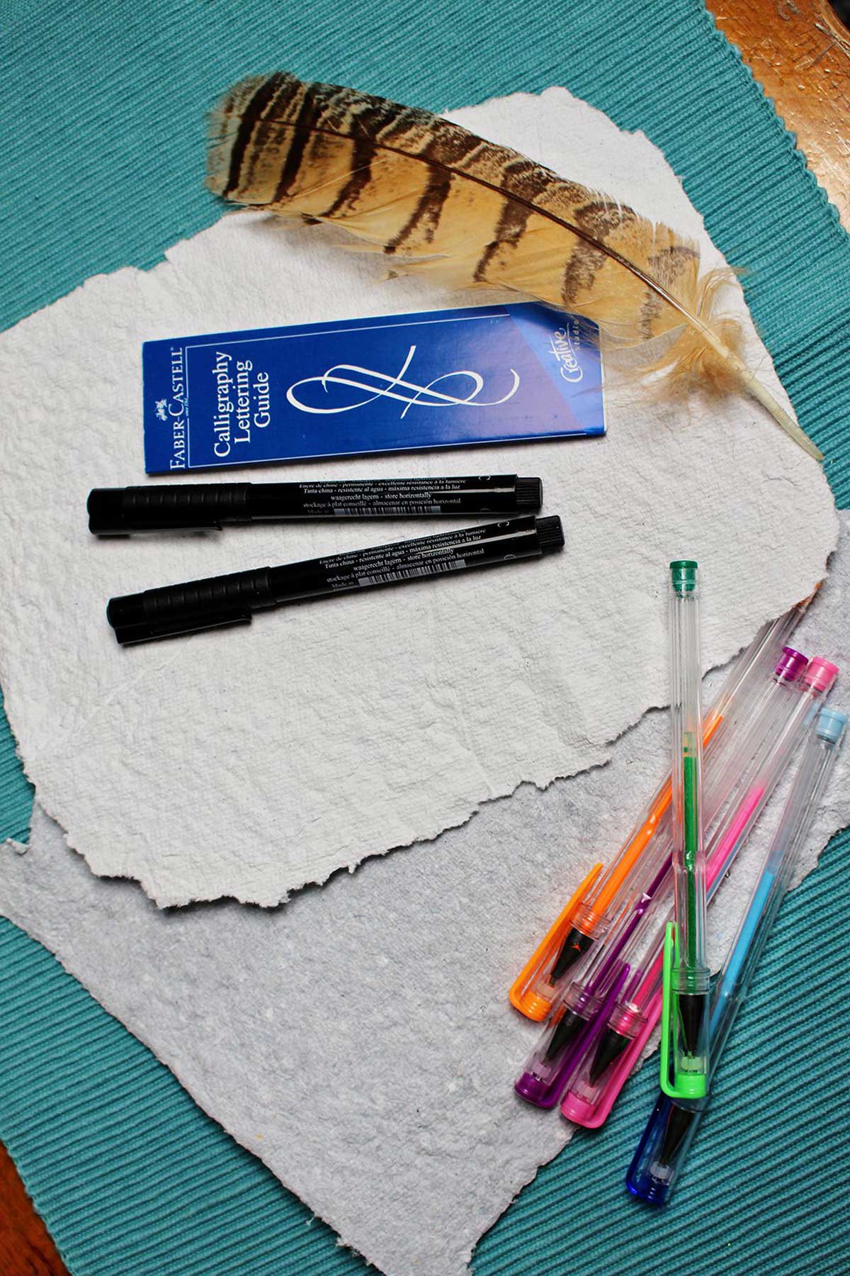 Páginas de papel reciclado, canetas gel, marcadores, uma pena.