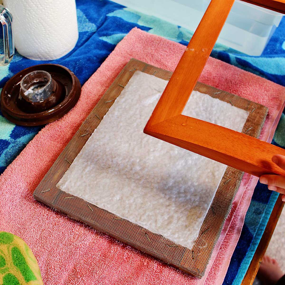 removendo o molde de uma moldura e molde com papel reciclado recém-feito.