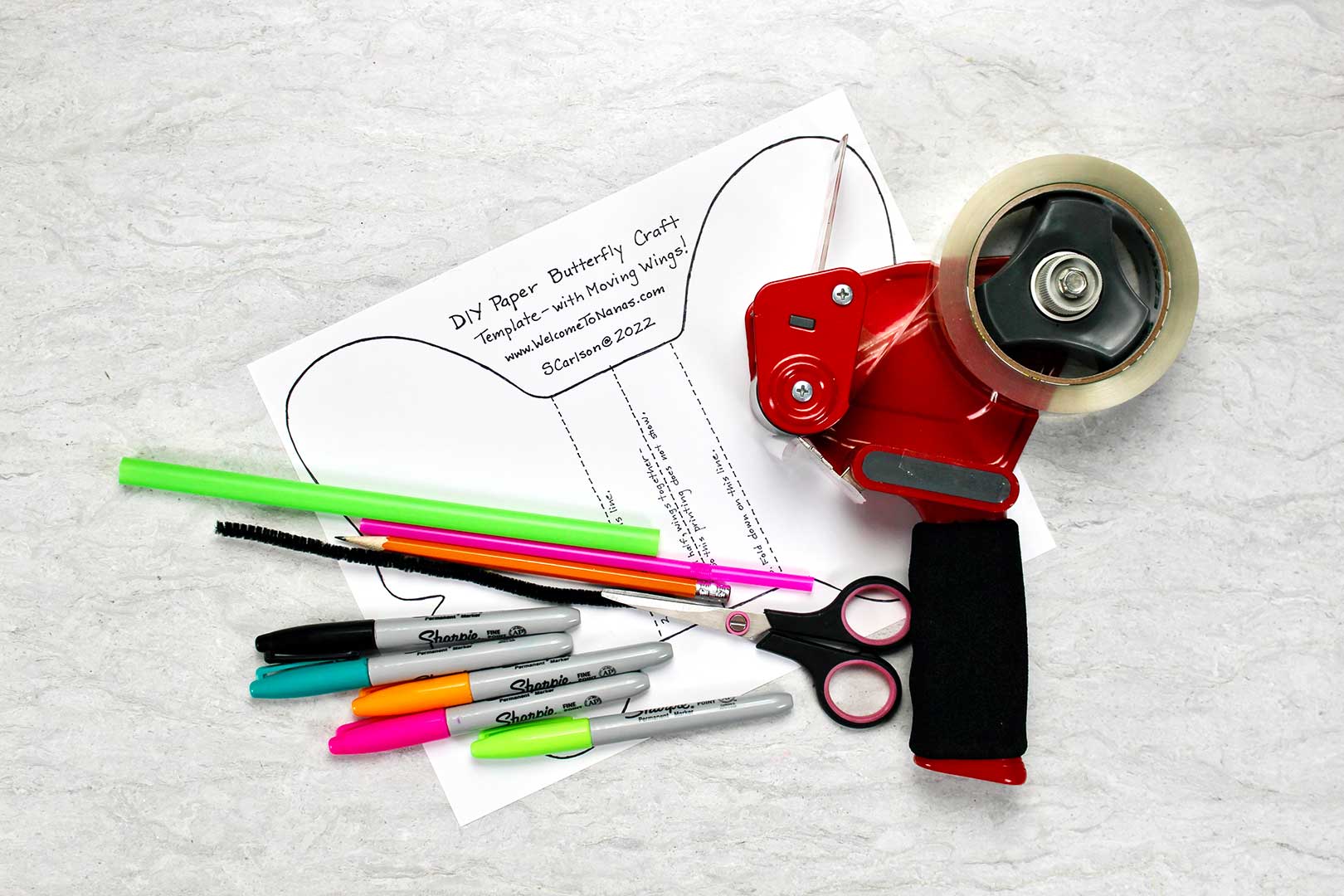 Fita adesiva, marcadores, tesouras pretas e canudos coloridos estão em cima do Template de Artesanato de Borboleta de Papel DIY.
