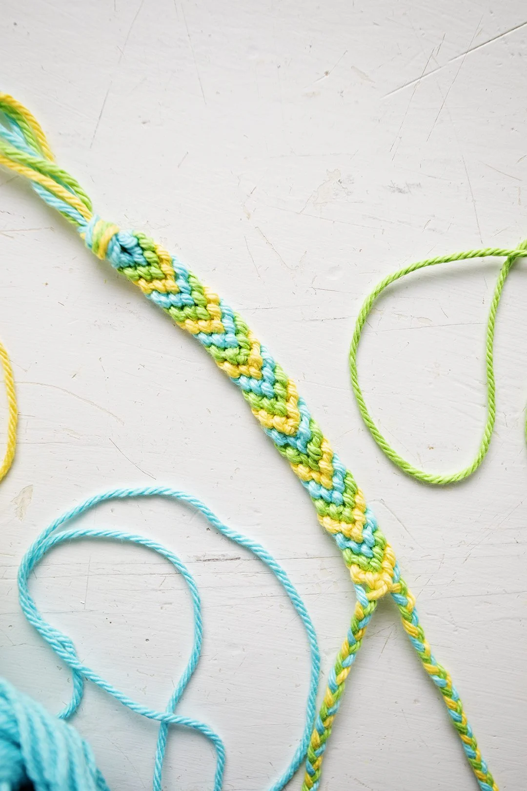 Um padrão de pulseira em Chevron feito a partir de fios azuis, verdes e amarelos.