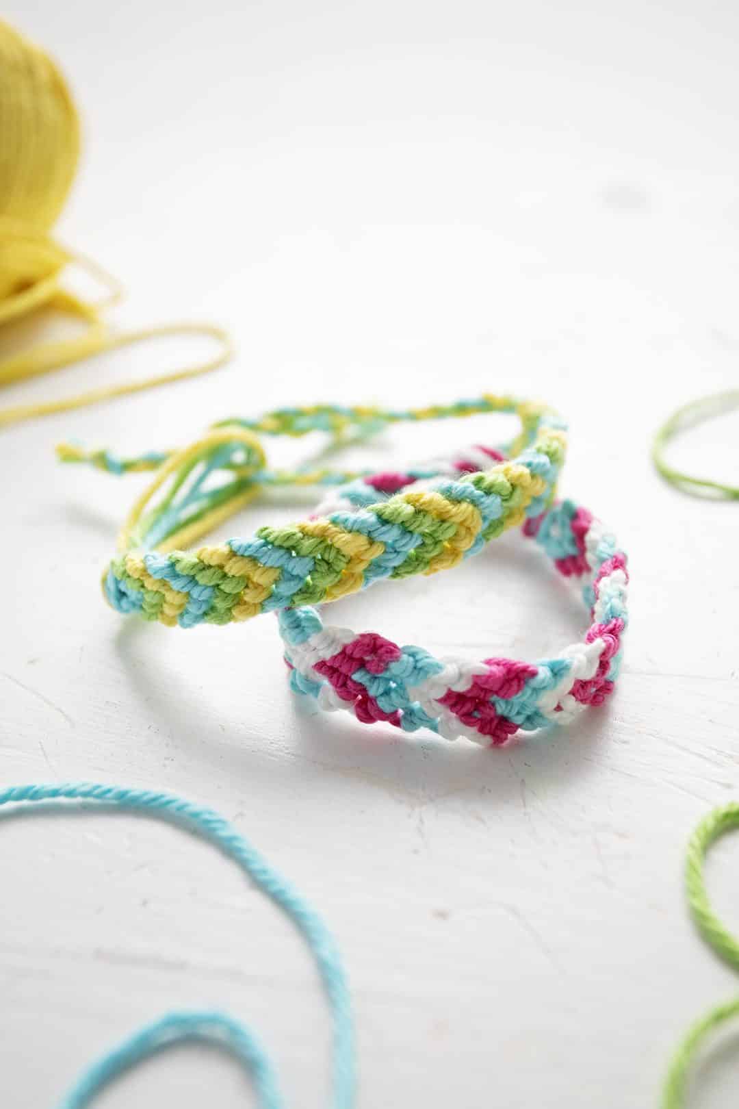 Duas pulseiras em padrão Chevron em linha de bordado verde, azul, amarelo, rosa e branca.