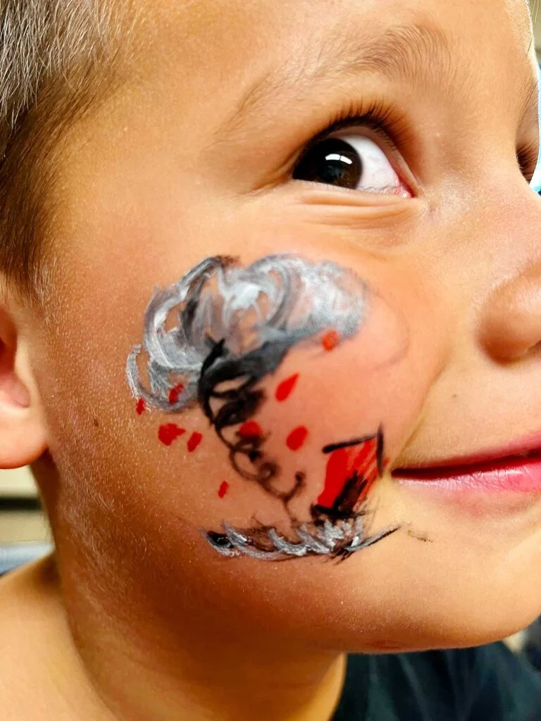 Menino jovem com olhos castanhos em close da pintura facial de tornado.