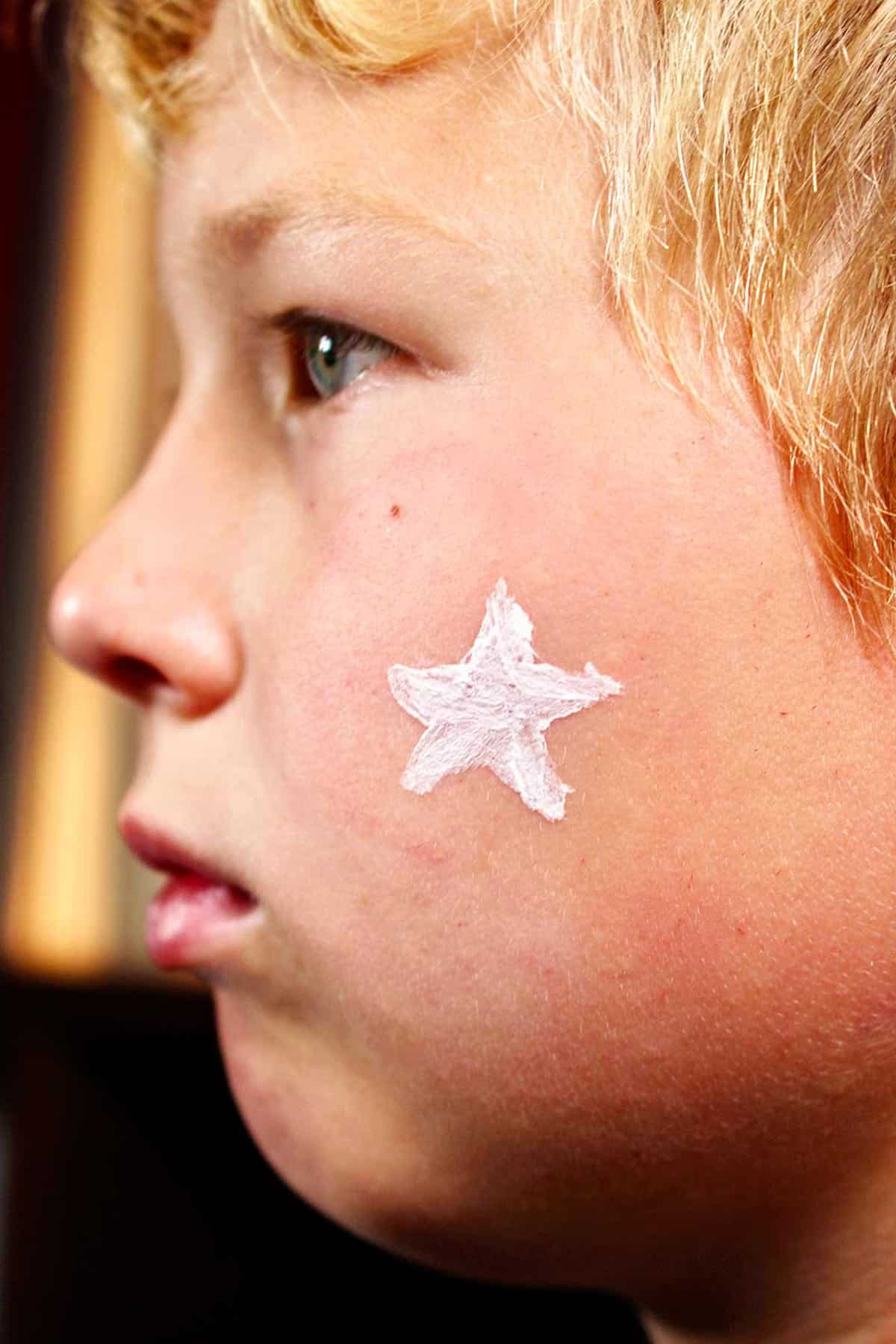 Perfil de menino com estrela branca pintada na bochecha.