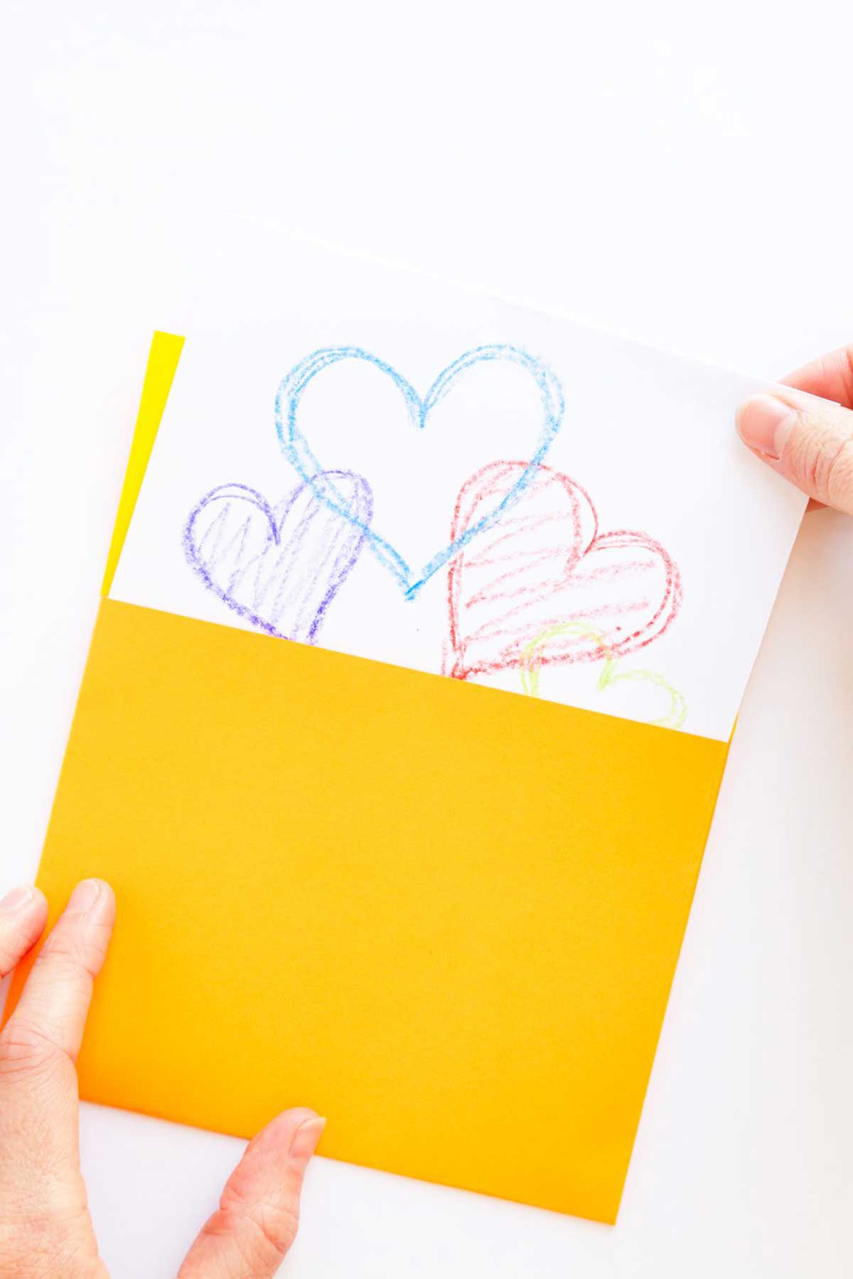 Puxando um cartão com corações coloridos de um envelope quadrado amarelo feito à mão.