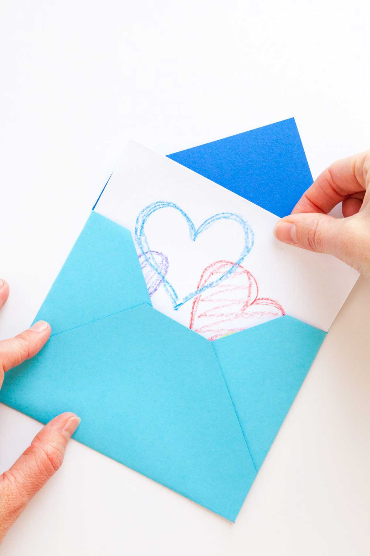 Puxando um cartão com corações de um envelope tradicional azul feito à mão.