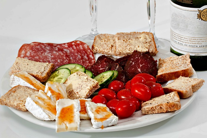 Tabuleiro branco de antipasti com carnes e legumes fatiados.