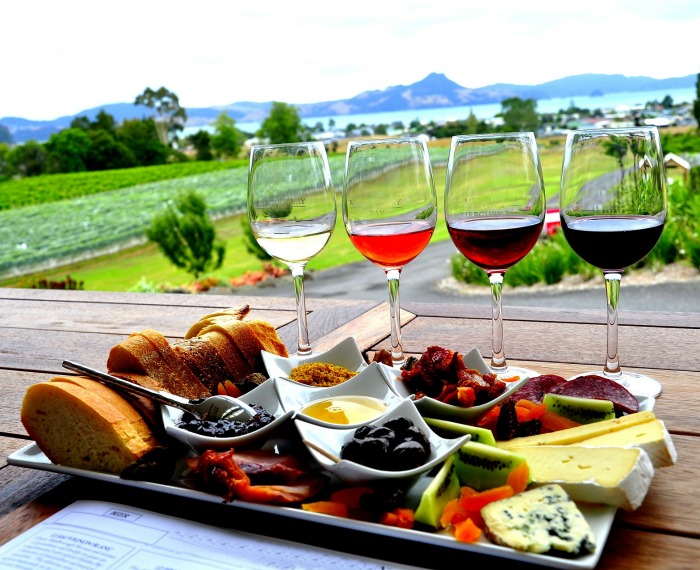 Tabuleiro de antipasto e taças de vinho em um ambiente externo.