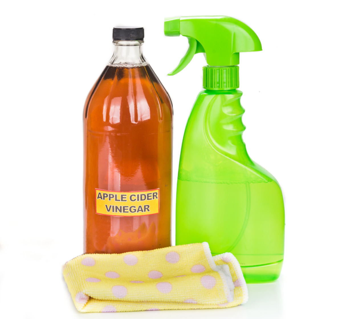 Vinagre de maçã em uma garrafa ao lado de um pano de limpeza e uma garrafa de spray verde.