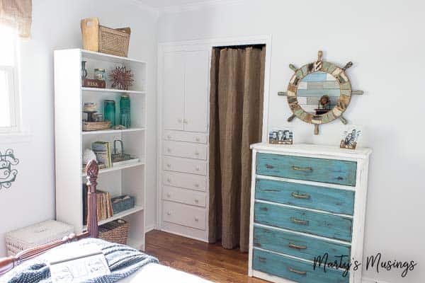 Quarto de estilo costeiro com cômoda azul pintada com tinta giz e acessórios