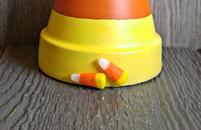 Doces de milho colados na parte inferior de um vaso de barro pintado de ponta-cabeça.