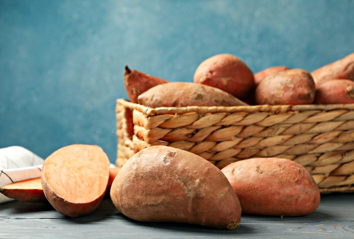 Uma cesta com batatas-doces orgânicas saudáveis e uma batata-doce cortada.