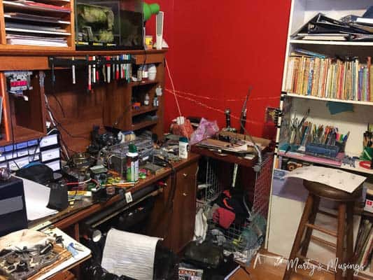 Uma escrivaninha cheia de coisas com uma estante de livros
