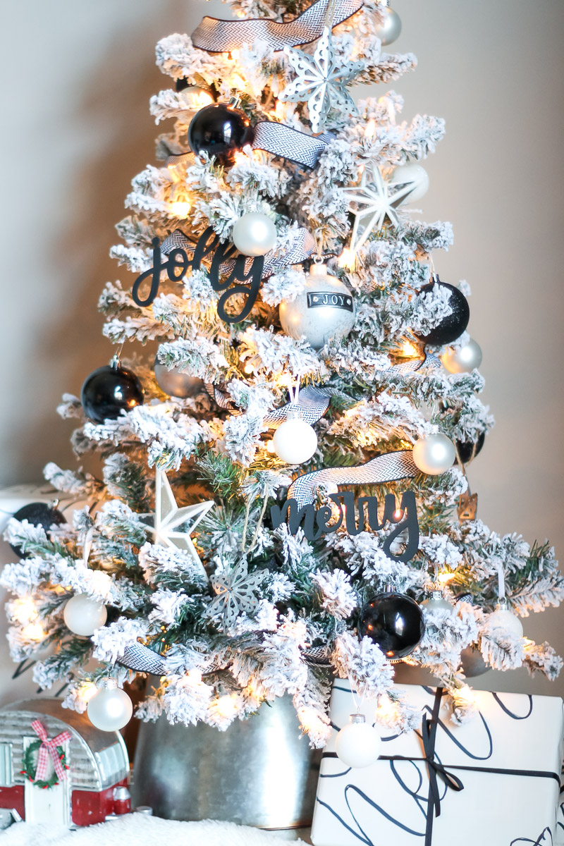 Árvore de Natal de mesa coberta de neve com ornamentos em preto e branco