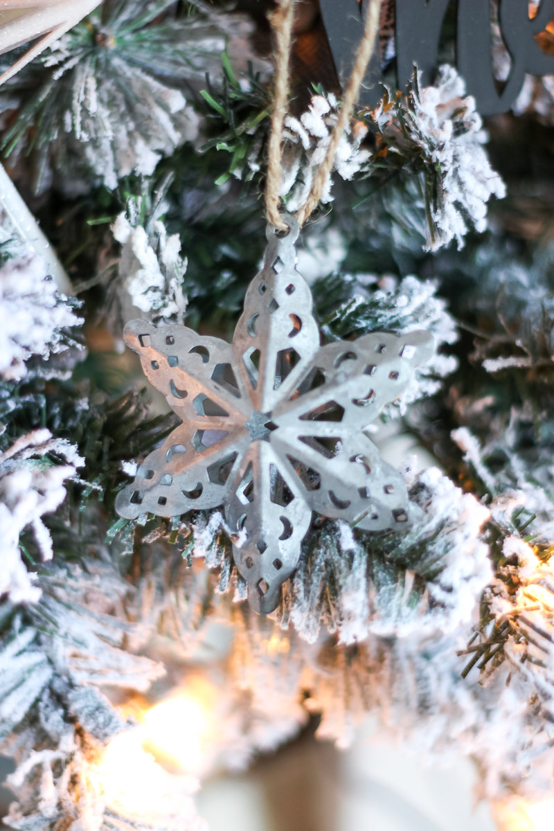 Ornamento de floco de neve em metal galvanizado de perto sobre a árvore coberta de neve