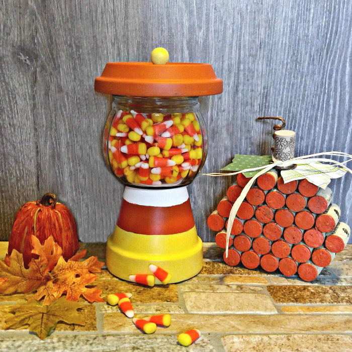 Um prato de doces DIY em uma vignette de outono com folhas de outono, uma abóbora falsa e o artesanato de abóbora de rolha de vinho.