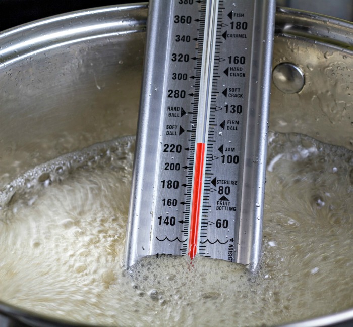 Usando um termômetro de confeitaria termômetro de confeitaria em uma panela de açúcar.