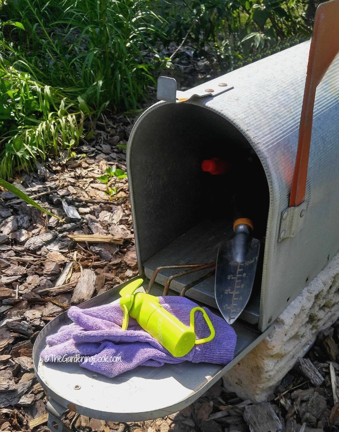 Caixa de correio com ferramentas de jardim, luvas e um ventilador mini.