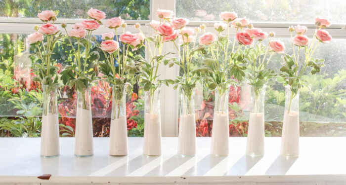 Garrafinhas de vidro da loja de desconto tingidas de rosa com flores rosa