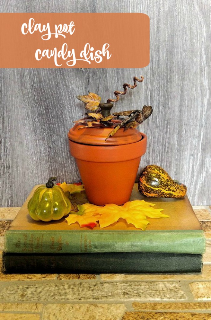 Prato de doces em forma de abóbora feito de um vaso de barro sobre uma pilha de livros antigos. O texto laranja diz prato de doces de vaso de barro.