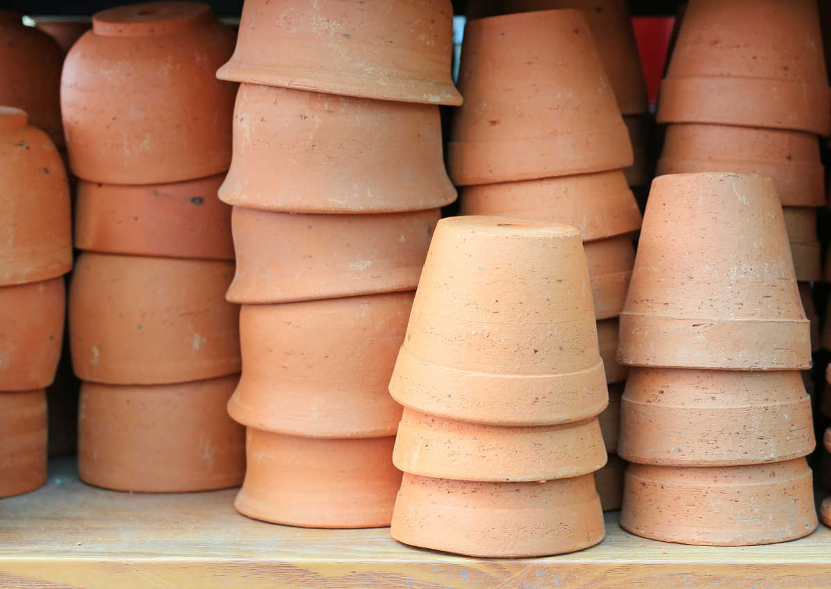 Vasos de barro limpos empilhados sobre uma prateleira de madeira.