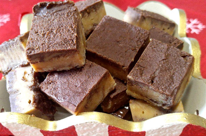 fudge perfeito fudge perfeito cortado em quadrados em uma caixa listrada de vermelho e branco.