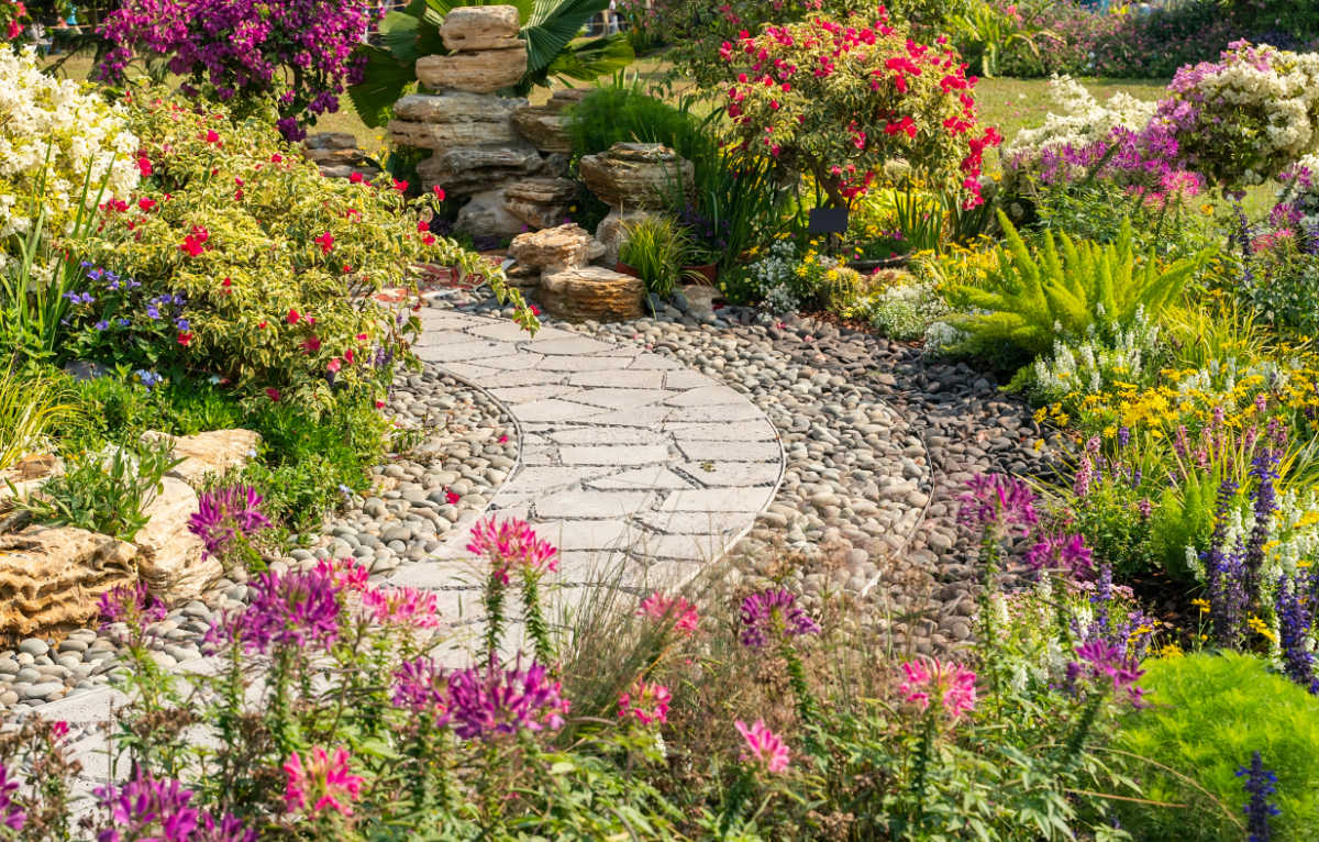 Um jardim de campo em flor com um caminho curvo passando através dele.