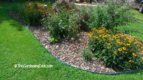 Um canteiro de flores com borda curva cercado por grama verde.