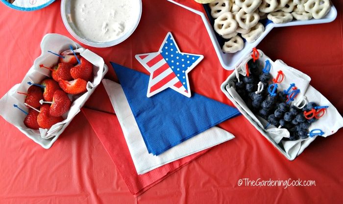 Morangos, dip, pretzels de iogurte e mirtilos com estrela de bandeira e toalhas vermelhas, brancas e azuis.