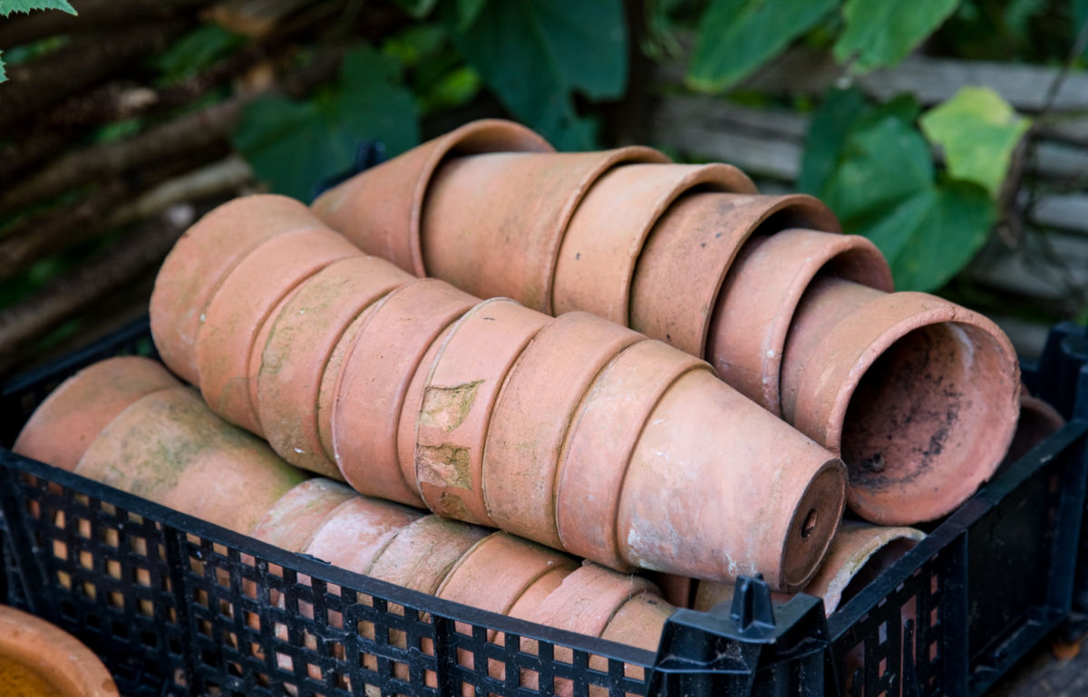 Montes de vasos de terracota sujos em uma caixa preta.